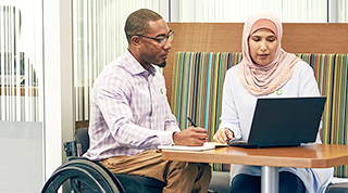 Un employé de la TD utilisant un fauteuil roulant collabore avec une collègue qui porte un hijab.
