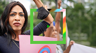 A person holds a sign and raises their hand in the air at a Pride parade. 