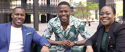 Brandon Gonez poses with two Black TD colleagues seated in green leather chairs in front of the Toronto-Dominion Centre. 