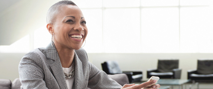 A Black businesswoman in a suit smiles during a meeting at a TD branch office. 