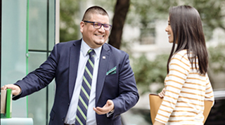 A TD colleague smiles as they welcome a customer into a branch to discuss their finances.