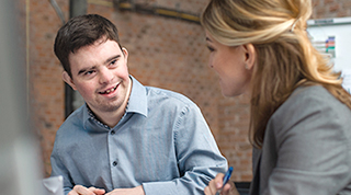 A person with a cognitive disability collaborates with a colleague in an office.