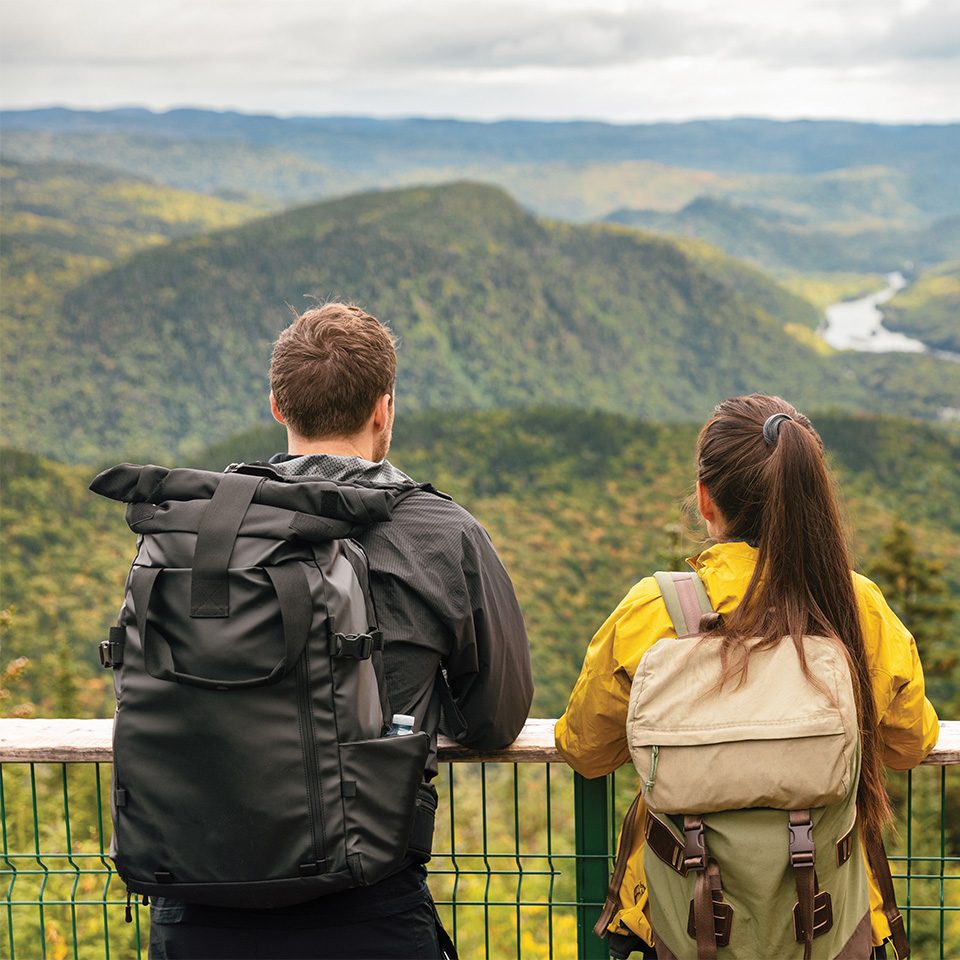 Man and woman looking out over forested mountains