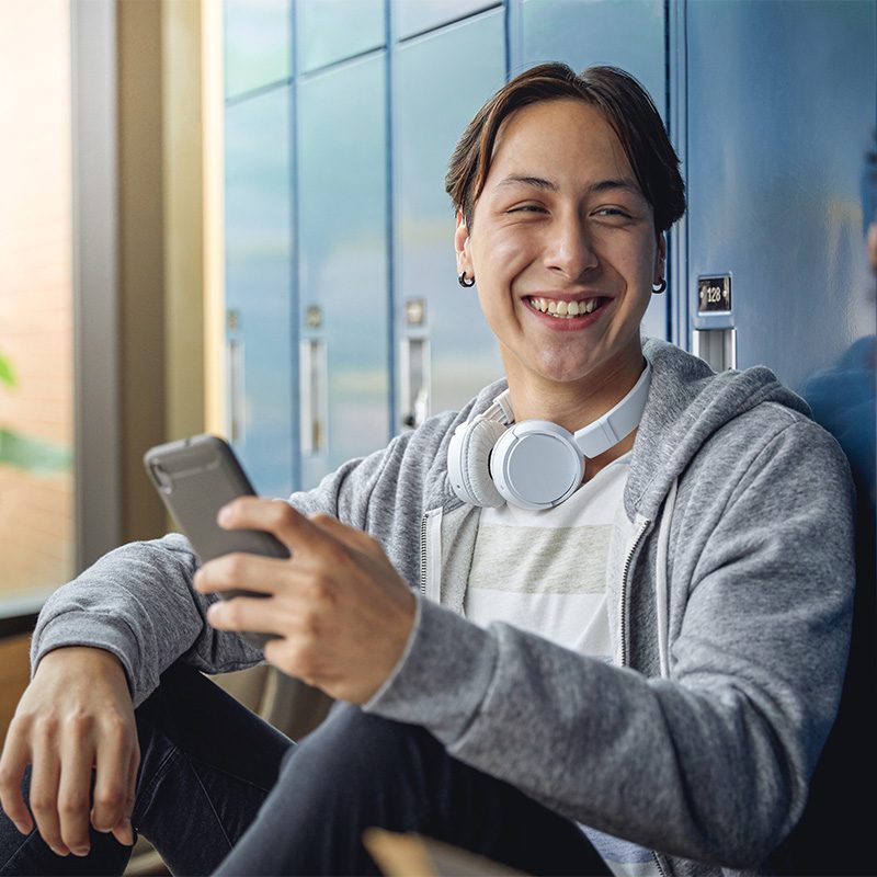 Smiling youth with headphones and cell phone