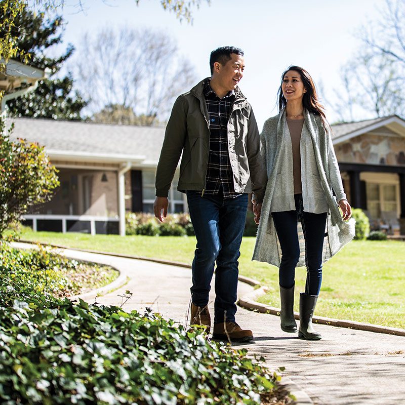 Man and woman walking in front of home