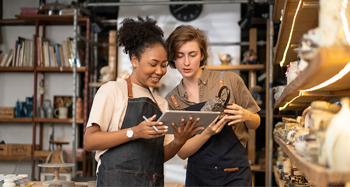 Two women in pottery studio viewing a tablet