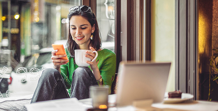 Woman holding coffee and phone in coffee shop