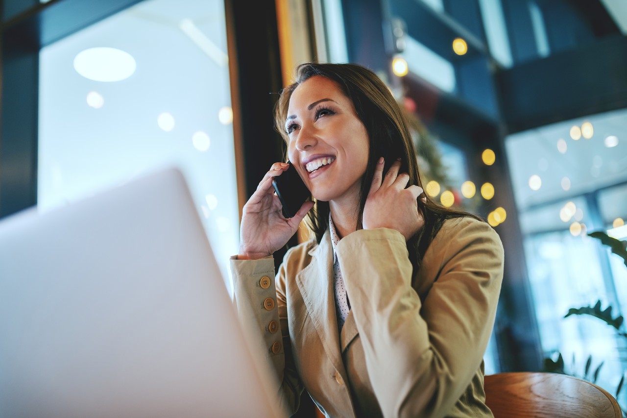 Attractive businesswoman sitting at working friendly cafe and using smart phone.