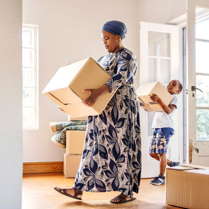 Une mère et son fils portent des boîtes dans leur nouvelle maison