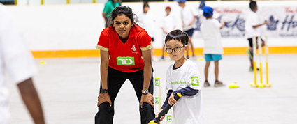 Un joueur des Jeunes joueurs de cricket TD debout à côté d’un joueur d’Équipe Canada qui attend pour frapper une balle.