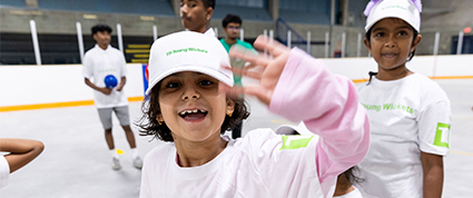 Une joueuse des Jeunes joueurs de cricket TD qui salue la caméra.