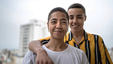 Deux personnes sourient devant leur immeuble d’habitation.