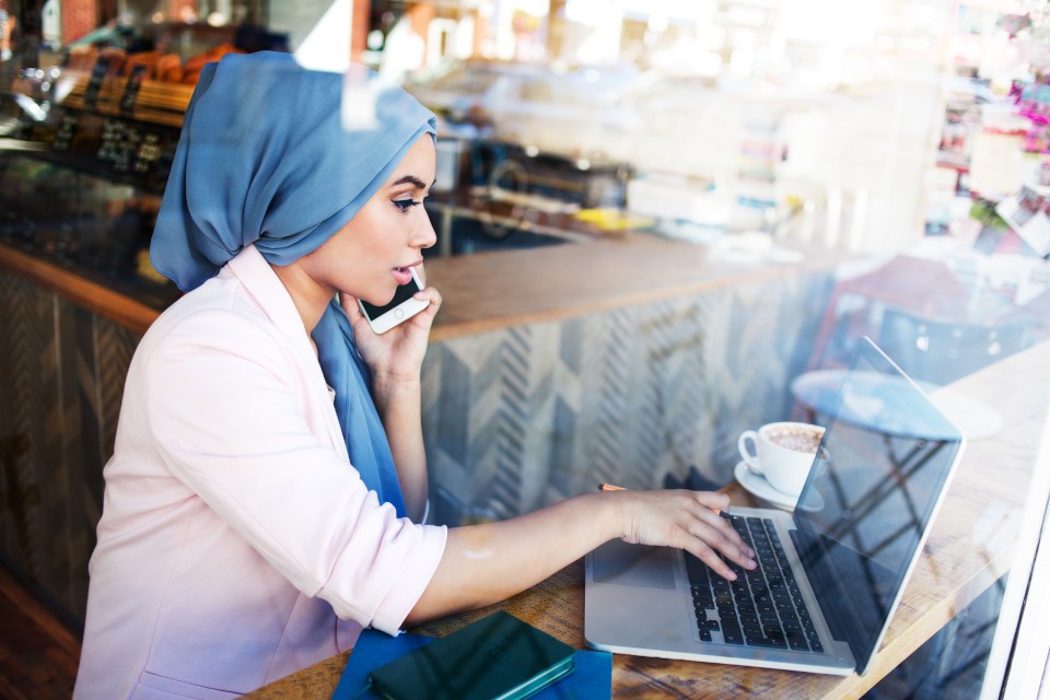 A woman works on a laptop in a café