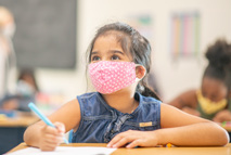 Elementary students working in a classroom wearing protective face masks during the COVID-19 pandemic