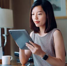 Un femme d’affaires utilise une tablette assise à son bureau à la maison