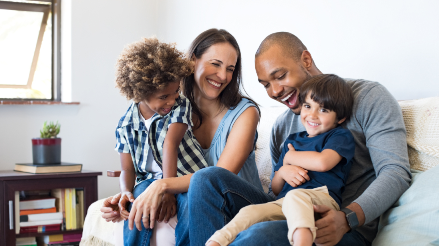 Diverse family sitting together on a couch and smiling.